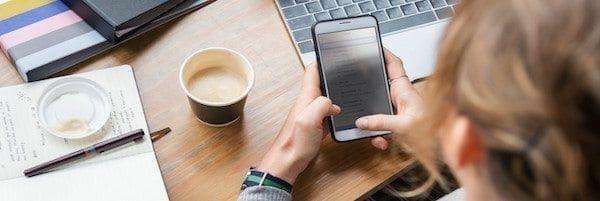 Person using a smartphone with a cup of coffee